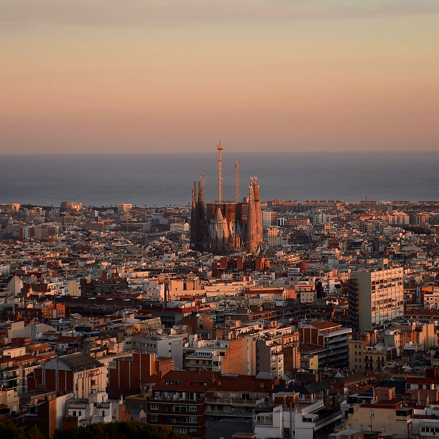 View of Barcelona at dusk, with the Sagrada Família in the centre and the sea behind